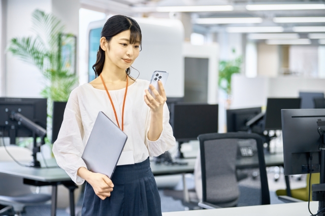 パソコンとスマートフォンで企業ホームページを確認する担当者