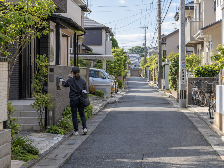 住宅街でチラシをポストへ配布するポスティングスタッフ