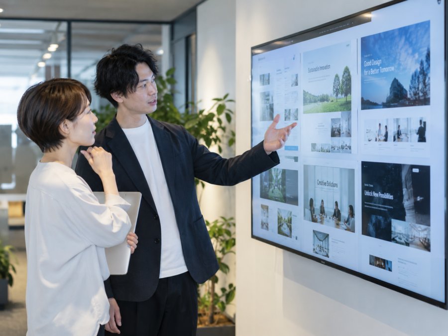 複数のホームページ制作事例を大型画面で確認するデザインチーム